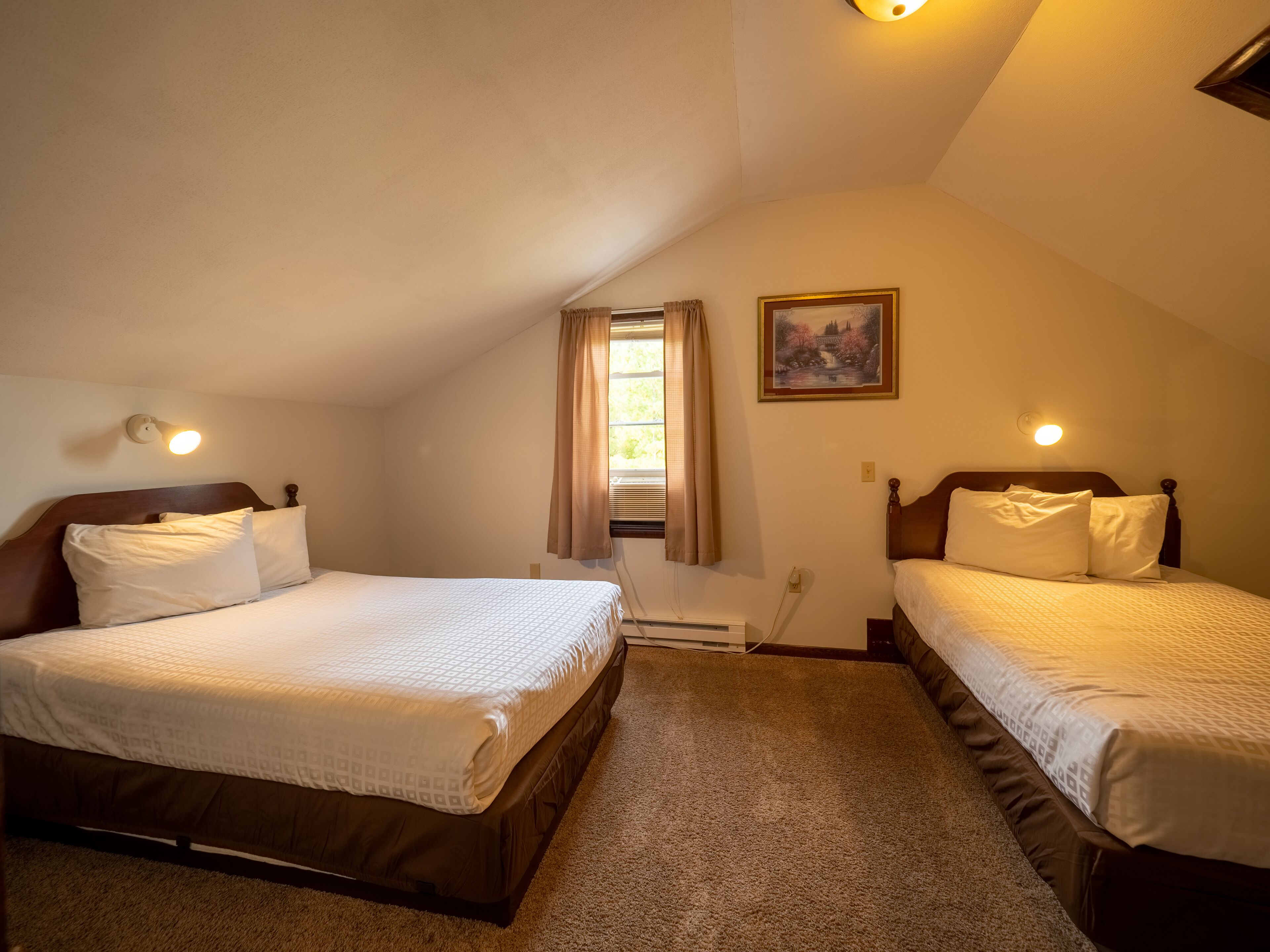 A room with two beds, a window with curtains, a painting on the wall, and a ceiling light.