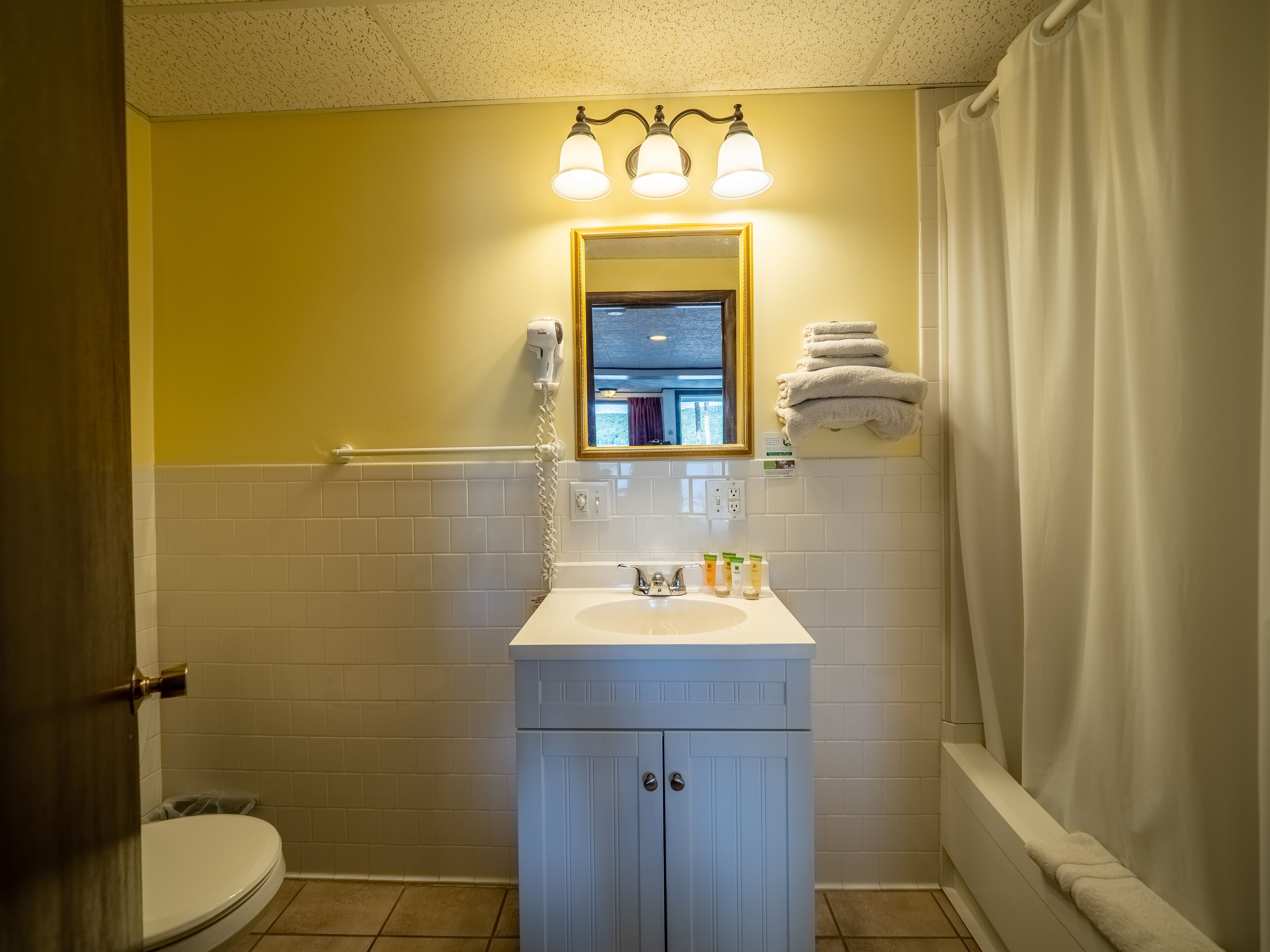Een badkamer met een wit wastafelmeubel, een spiegel en een handdoekhouder.