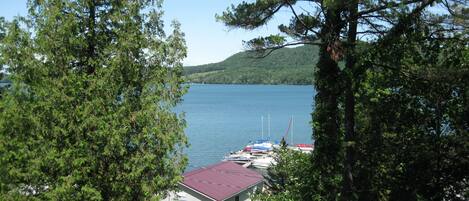 A lakeside cabin with a red roof, surrounded by trees and docked boats.