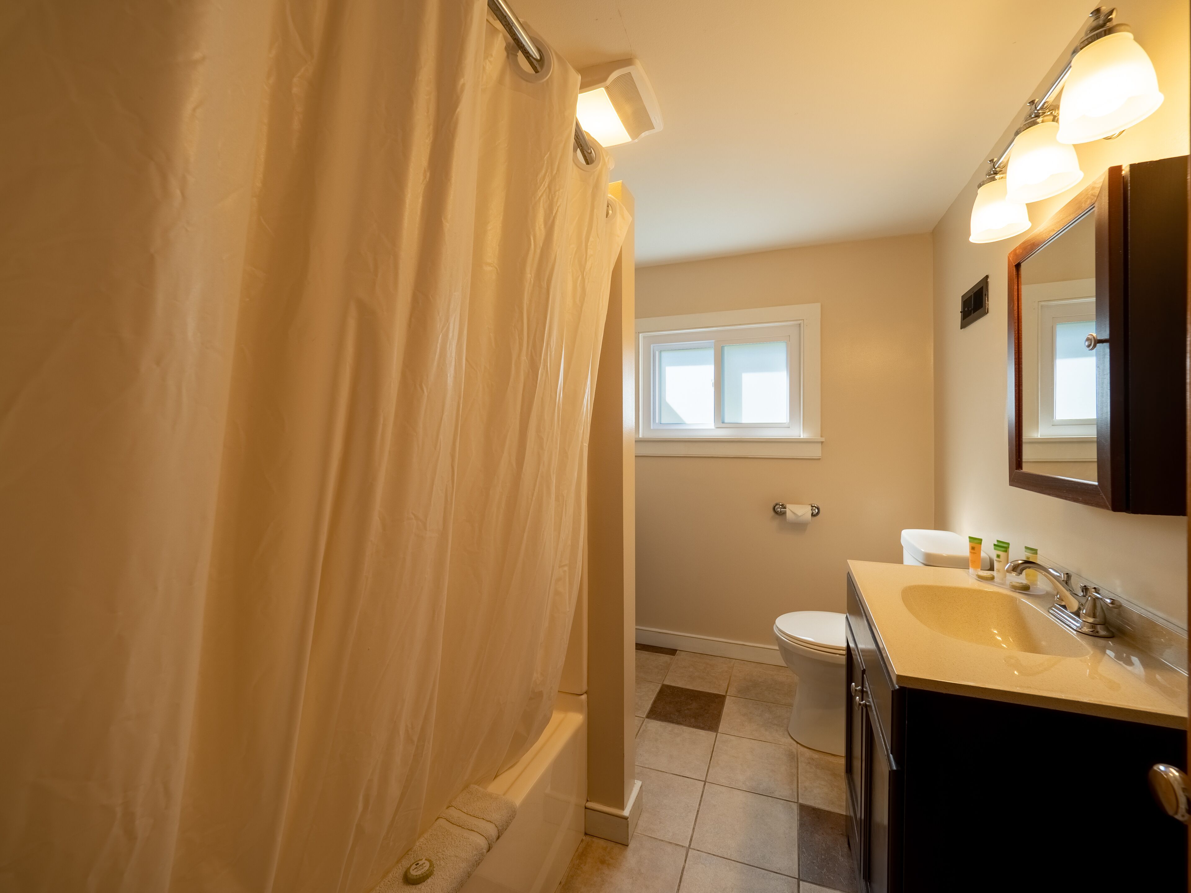 A bathroom with a bathtub, toilet, sink, and a window.