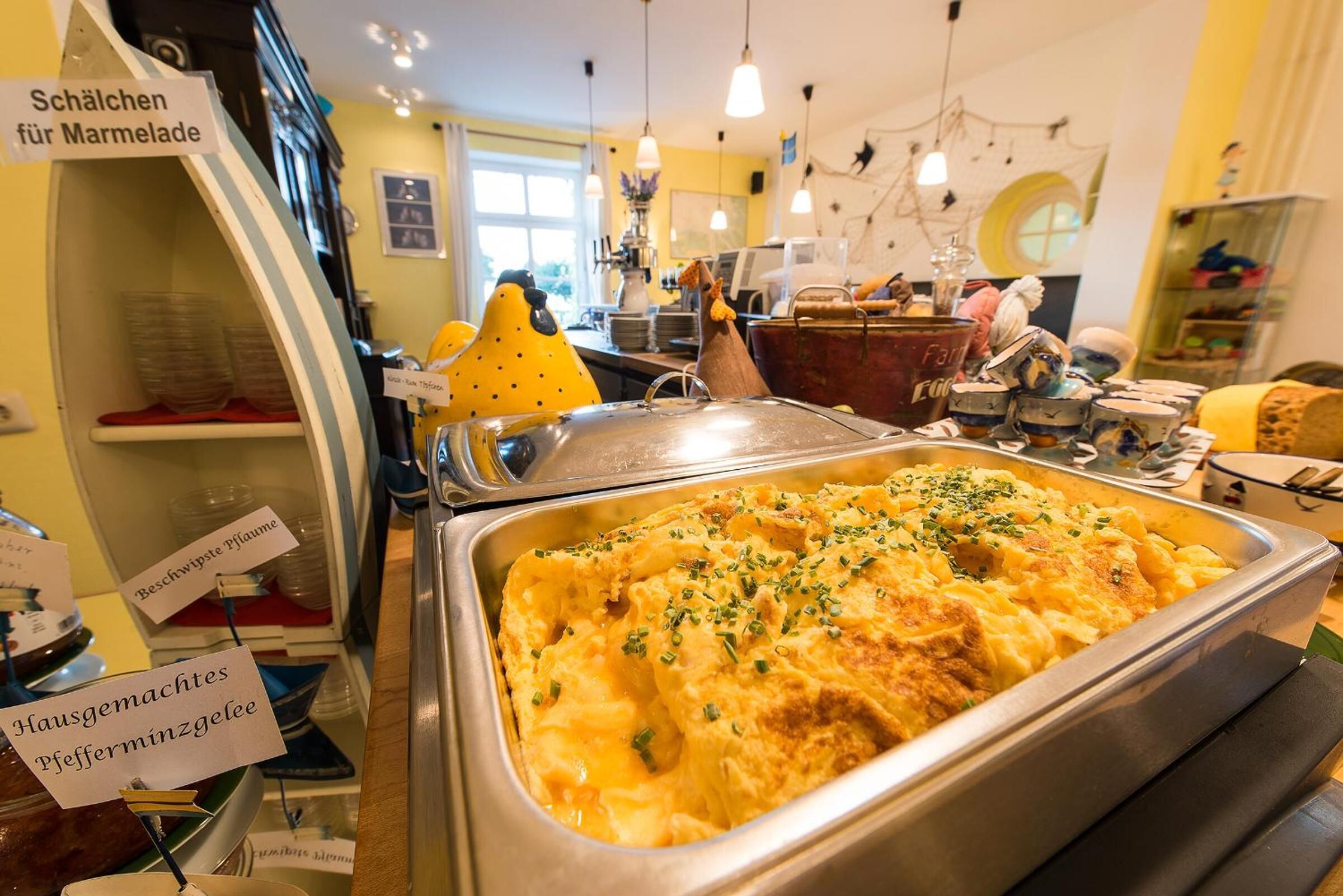 A buffet area with a variety of dishes, including a large serving of macaroni and cheese, and signs indicating different types of food.
