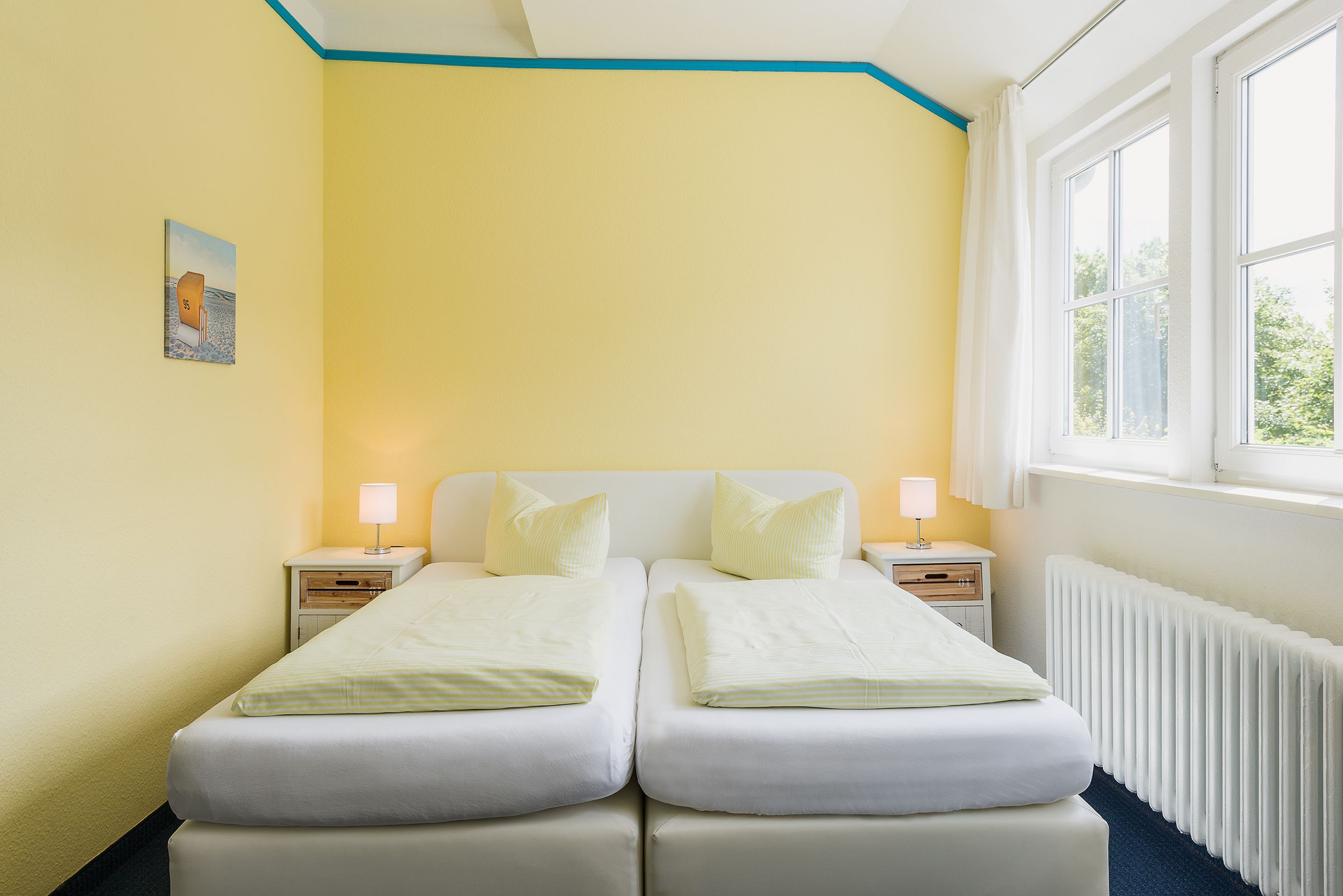 A double bed with two pillows, a bedside table with a lamp, and a window with curtains.