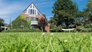 A house with a sloped roof, a balcony, and a grassy yard.