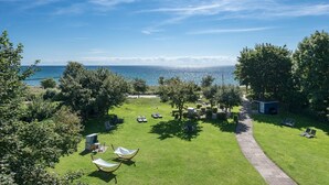 A grassy outdoor area with lounge chairs and a pathway leading to a small structure. - Hotel am Wind (Grossenbrode)