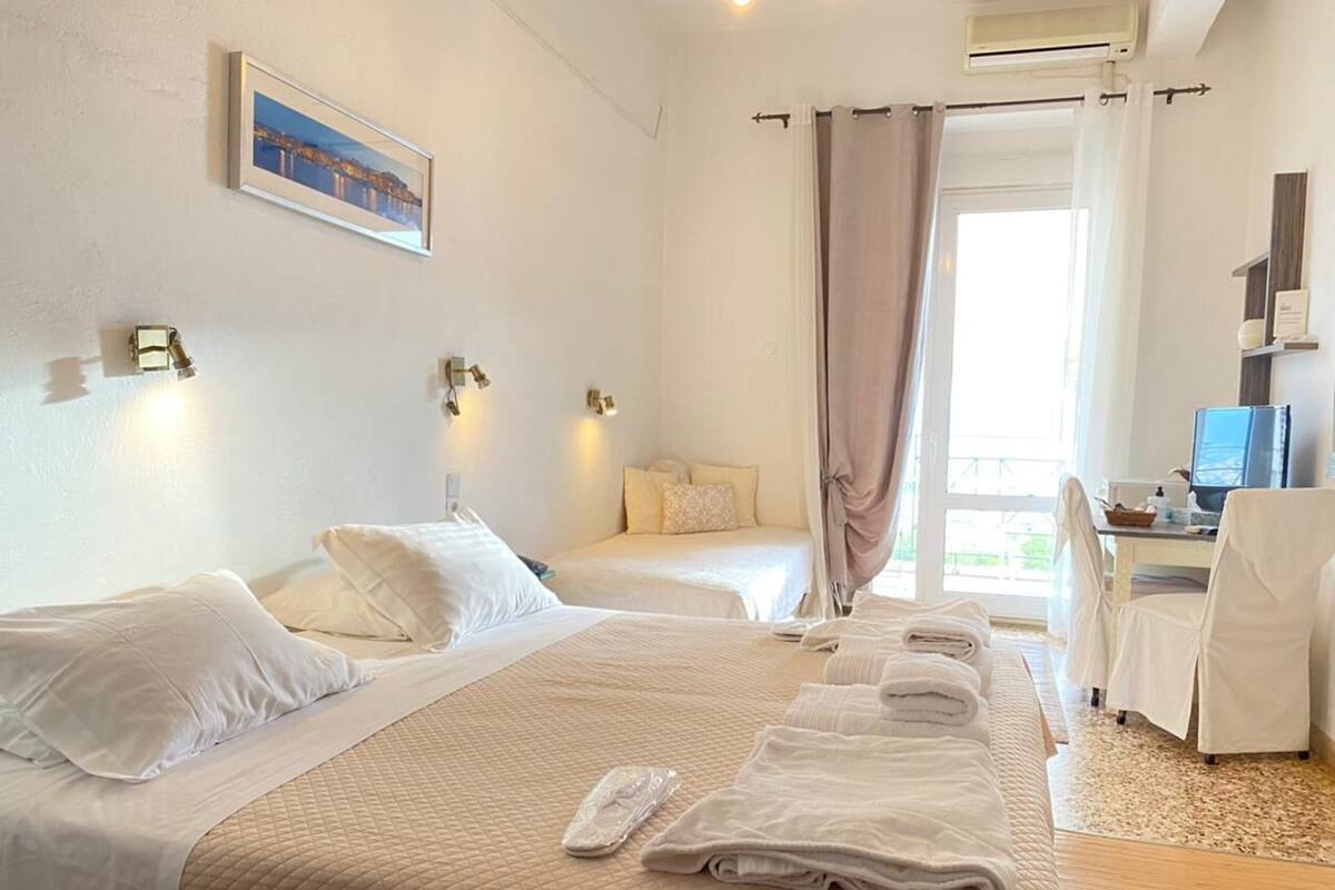 Habitación de hotel con dos camas, un escritorio, una silla y una ventana con cortinas.