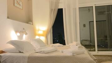A hotel room with a bed, two bedside lamps, a window with curtains, and a view of the city at night.