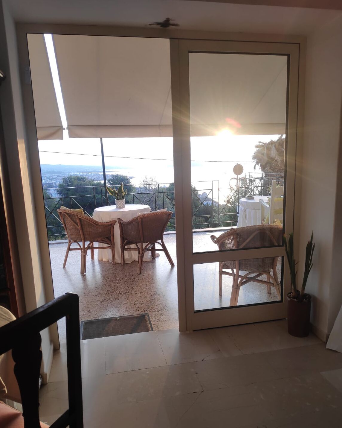 A room with a sliding glass door leading to an outdoor balcony with wicker furniture and a potted plant.