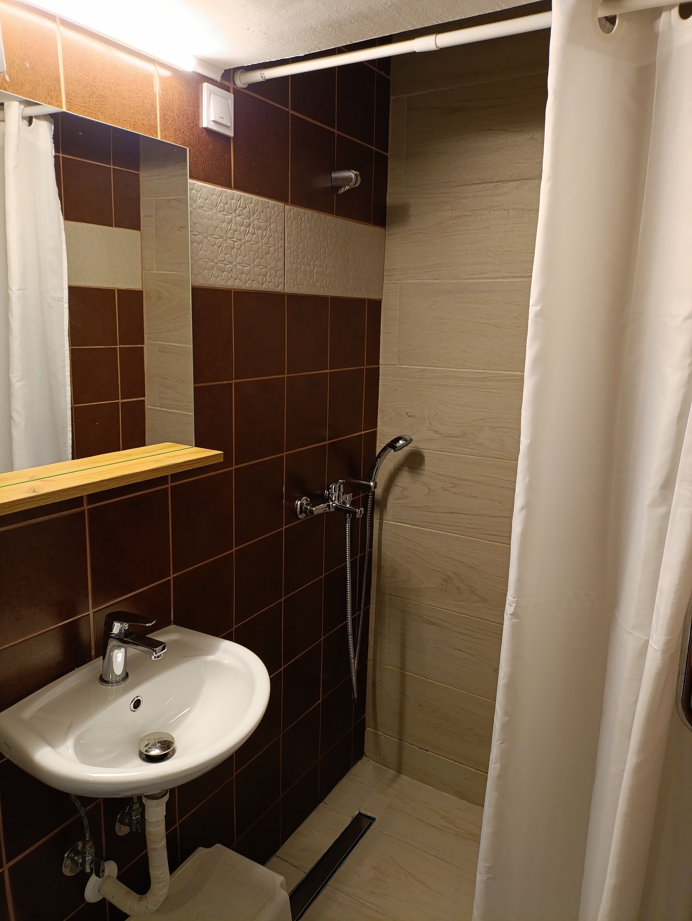 Une salle de bain équipée d’un lavabo, d’un miroir, d’une douche et d’un porte-serviettes.