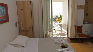 Une chambre d’hôtel comprenant un lit, une armoire en bois, un bureau avec une chaise et un balcon avec une table et des chaises.