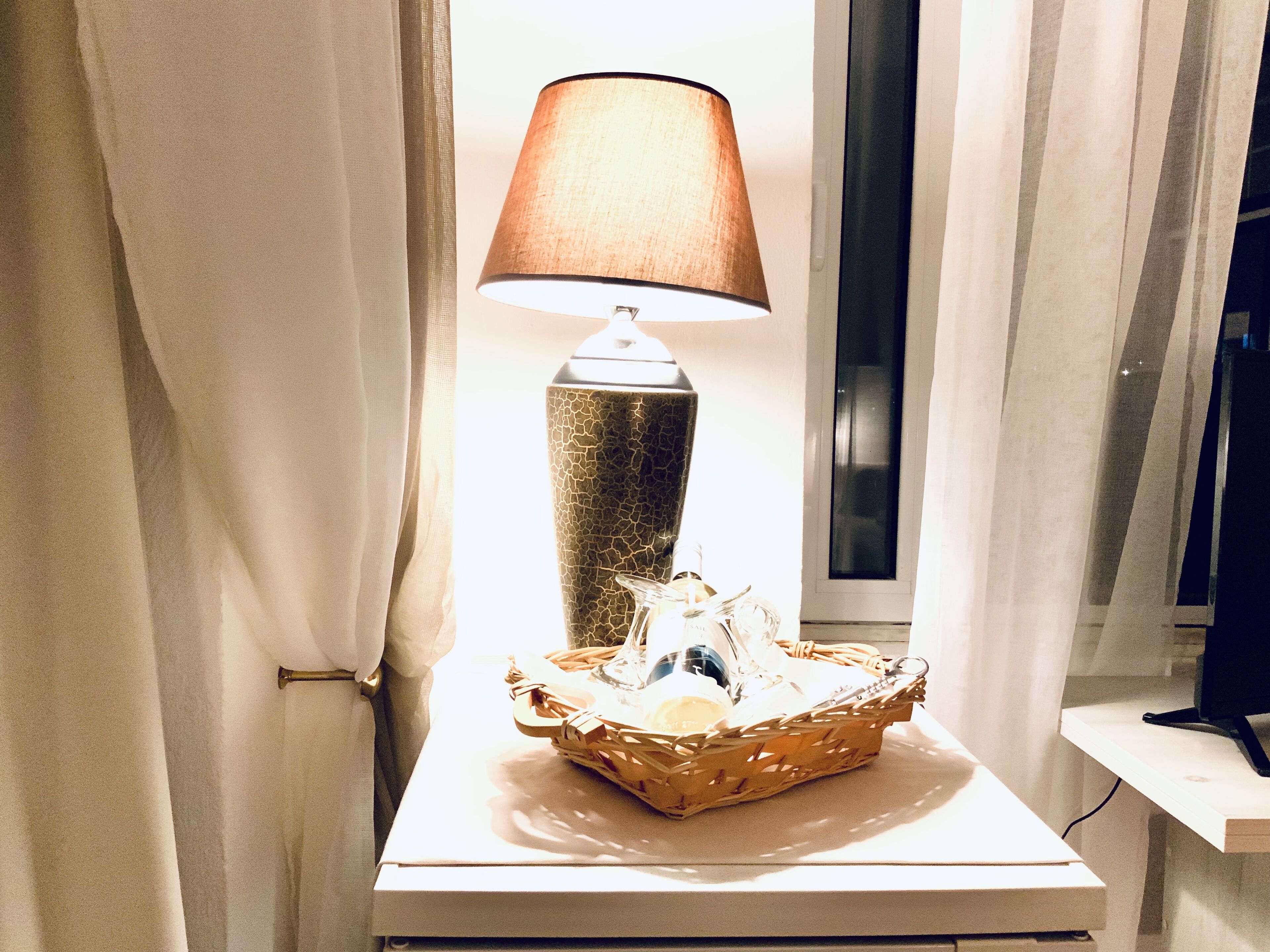 Una lámpara sobre una mesita de noche con una cesta de objetos.