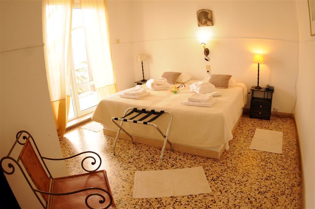 Una habitación de hotel con una cama, una silla, una mesita de noche y una lámpara.