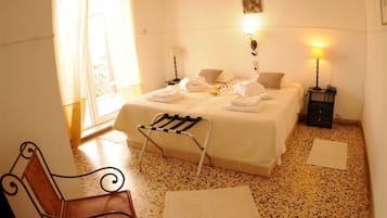 Una habitación de hotel con una cama, una silla, una mesita de noche y una lámpara.