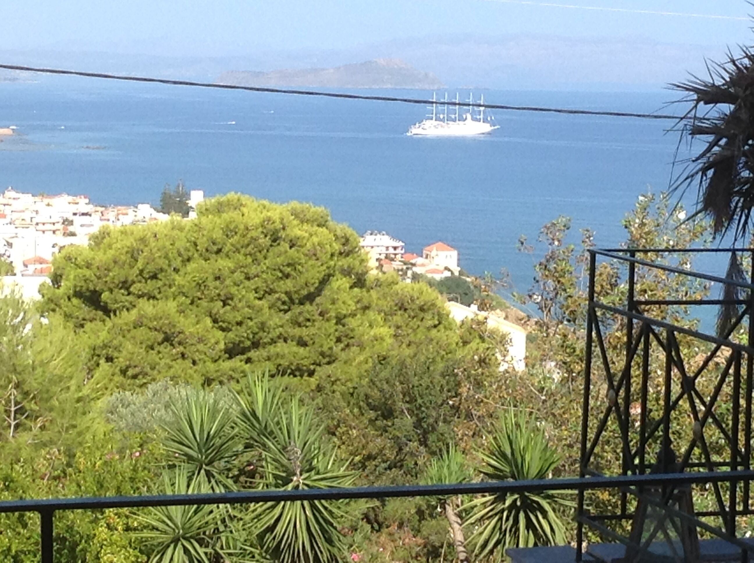 A coastal town with a ship in the distance, surrounded by greenery and buildings.