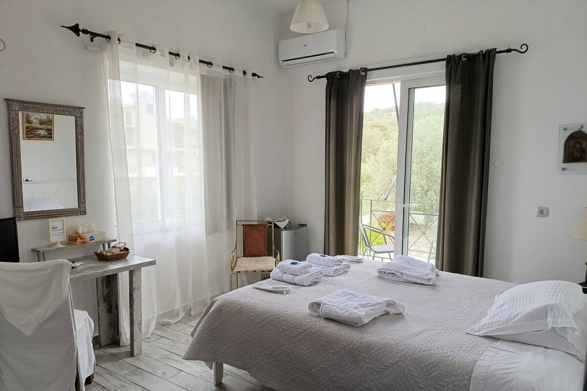 Una habitación de hotel con cama, escritorio, silla y vistas al exterior.