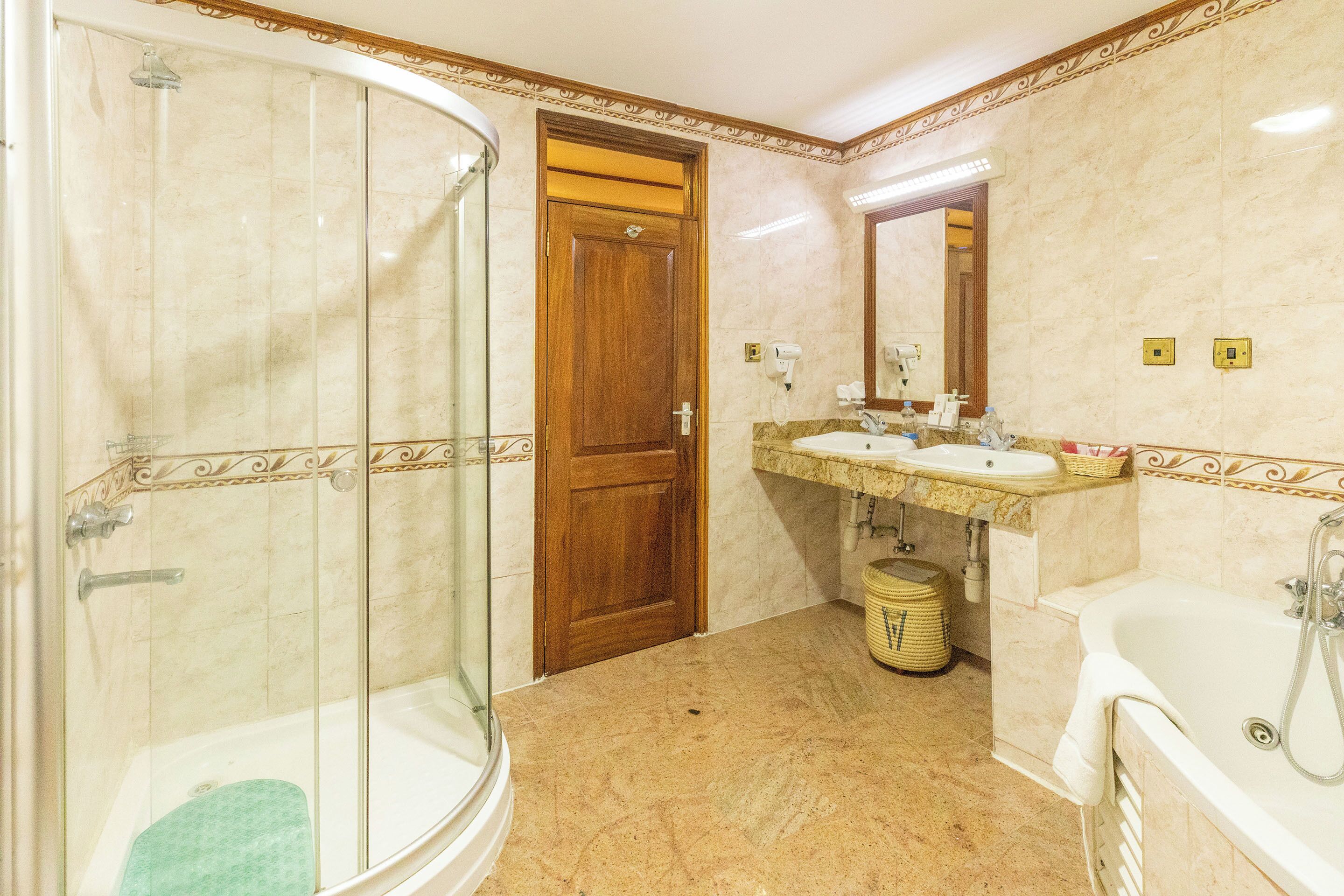 Un baño con ducha de vidrio, puerta de madera, lavamanos con espejo y bañera.