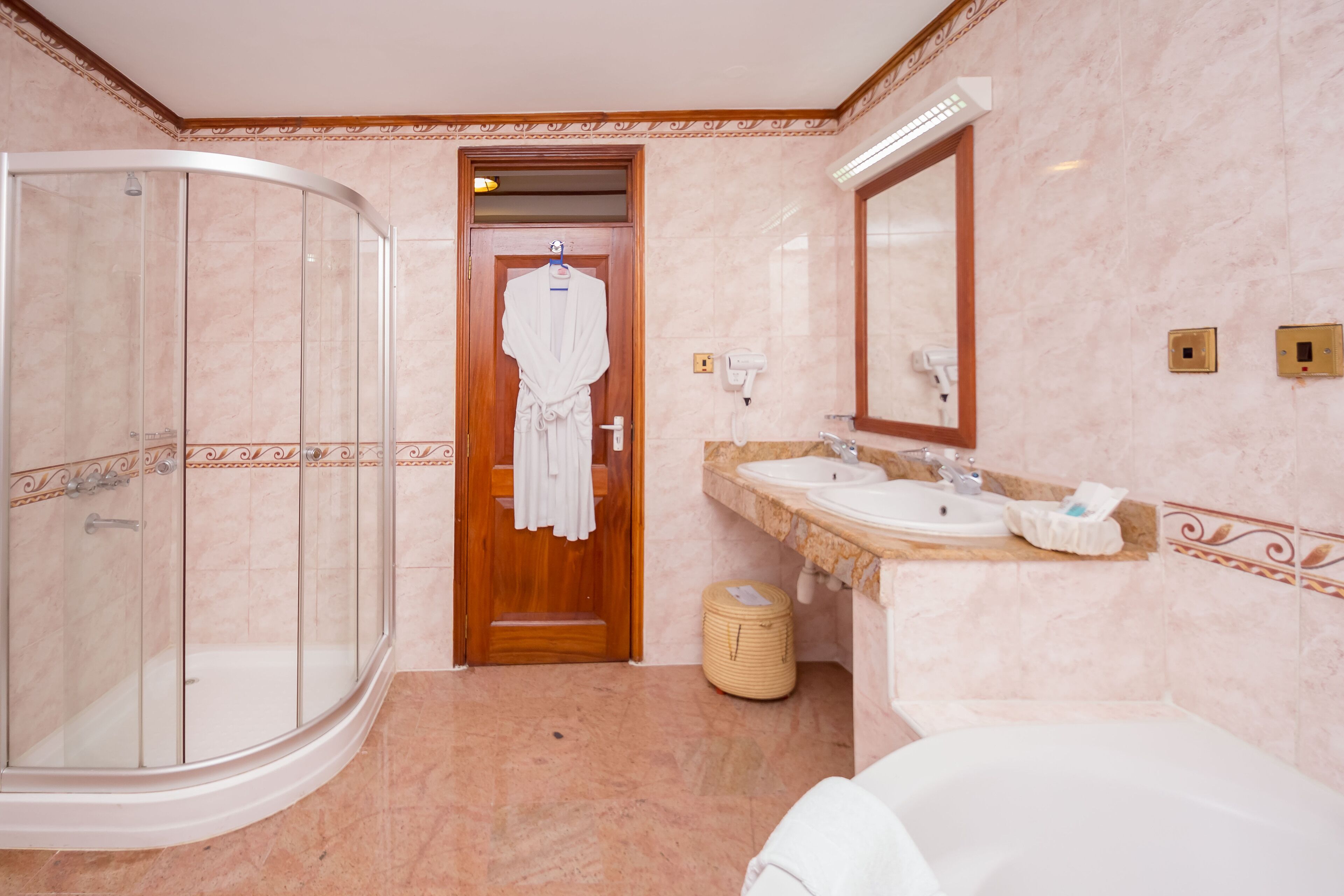 A modern bathroom with a glass-enclosed shower, a wooden door leading to a walk-in closet, and a vanity with a sink and mirror.