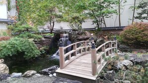 A wooden bridge over a small stream with a waterfall, surrounded by rocks and greenery. - APA Hotel Sapporo Susukino Ekimae (Sapporo)