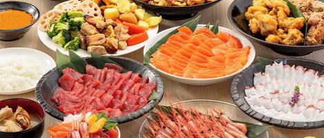 A variety of dishes including sashimi, seafood, and vegetables.
