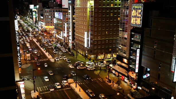 A busy urban street at night with illuminated buildings and vehicles. - APA Hotel Sapporo Susukino Ekimae (Sapporo)