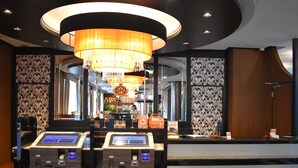 A hotel reception area with a modern design, featuring a chandelier, a reception desk, and self-service kiosks. - APA Hotel Sapporo Susukino Ekimae (Sapporo)