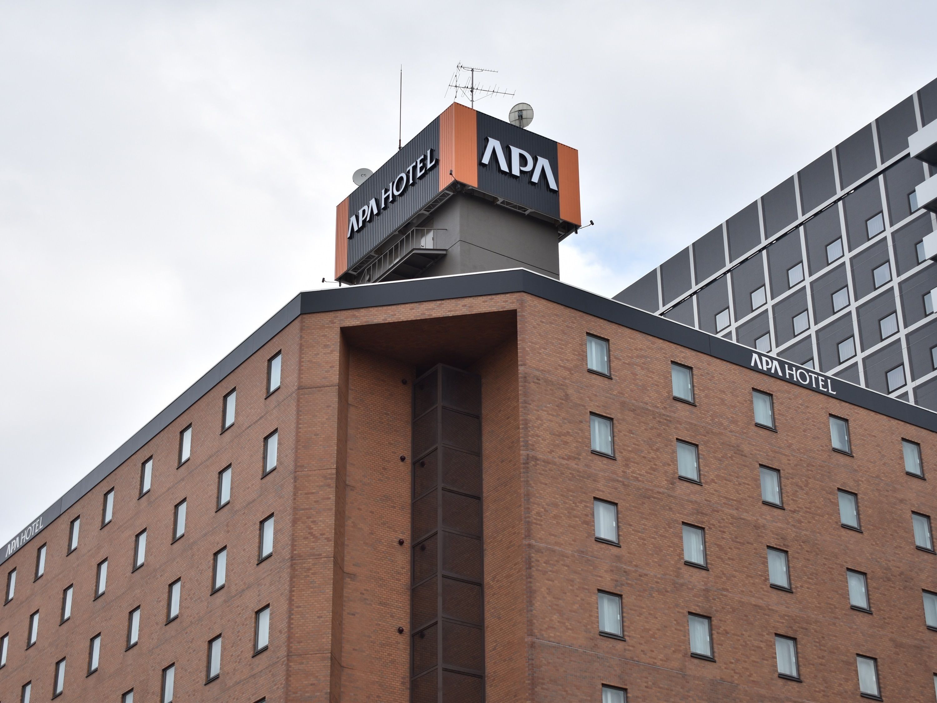 A hotel building with a prominent 'APA HOTEL' sign on the roof.