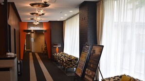 A hotel lobby with a reception desk, a chandelier, a seating area with floral-patterned chairs, and a brick accent wall. - APA Hotel Sapporo Susukino Ekimae (Sapporo)