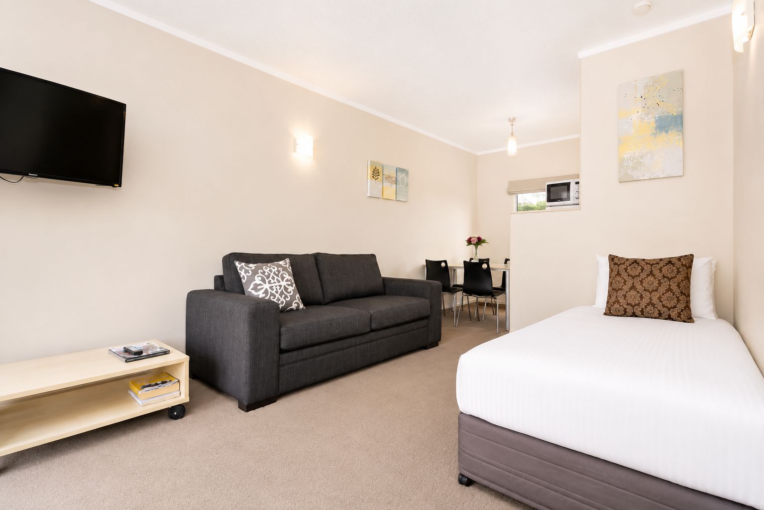 A hotel room with a bed, a sofa, a TV, a desk, and a chair.