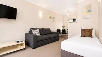 A hotel room with a bed, a sofa, a TV, a desk, and a chair.