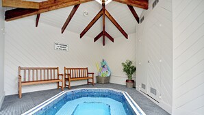 An indoor swimming pool with a tiled floor, wooden benches, and a ceiling with wooden beams. - Takapuna Motor Lodge (Auckland)