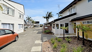 A street view of a residential area with houses, a reception sign, and a parked car. - Takapuna Motor Lodge (Auckland)