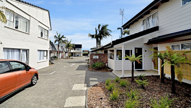 A street view of a residential area with houses, a reception sign, and a parked car. - Takapuna Motor Lodge (Auckland)