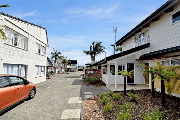 A street view of a residential area with houses, a reception sign, and a parked car. - Takapuna Motor Lodge (Auckland)