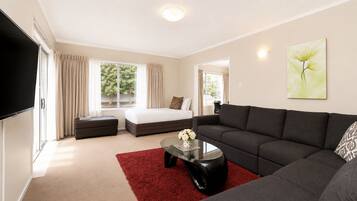 A modern living room with a sofa, a coffee table, a TV, and a bed.