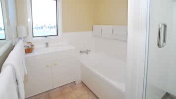 Un baño con bañera, ventana, lavabo y ducha.