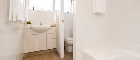 A modern bathroom with a sink, toilet, and bathtub.
