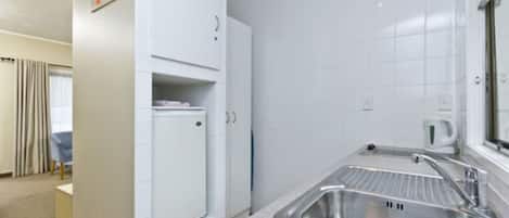 A compact kitchen with white cabinets, a stainless steel sink, and a window above the sink.