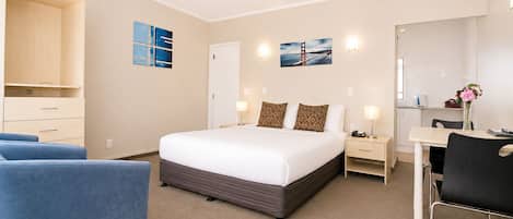 Una habitación de hotel con cama, mesitas de noche, escritorio, silla y armario.