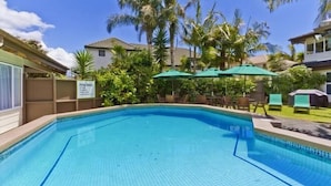 A swimming pool with tiled edges, surrounded by palm trees and a sign indicating 'Pool Area'. - Takapuna Motor Lodge (Auckland)