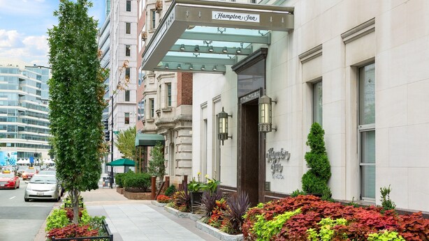 A Hampton Inn hotel with a classic facade, a covered entrance, and a well-maintained sidewalk with plants. - Hampton Inn Washington, D.C./White House (Washington)