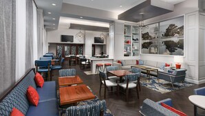 A modern hotel lobby with seating areas, a bar, and a large window with a view of a building. - Hampton Inn Washington, D.C./White House (Washington)