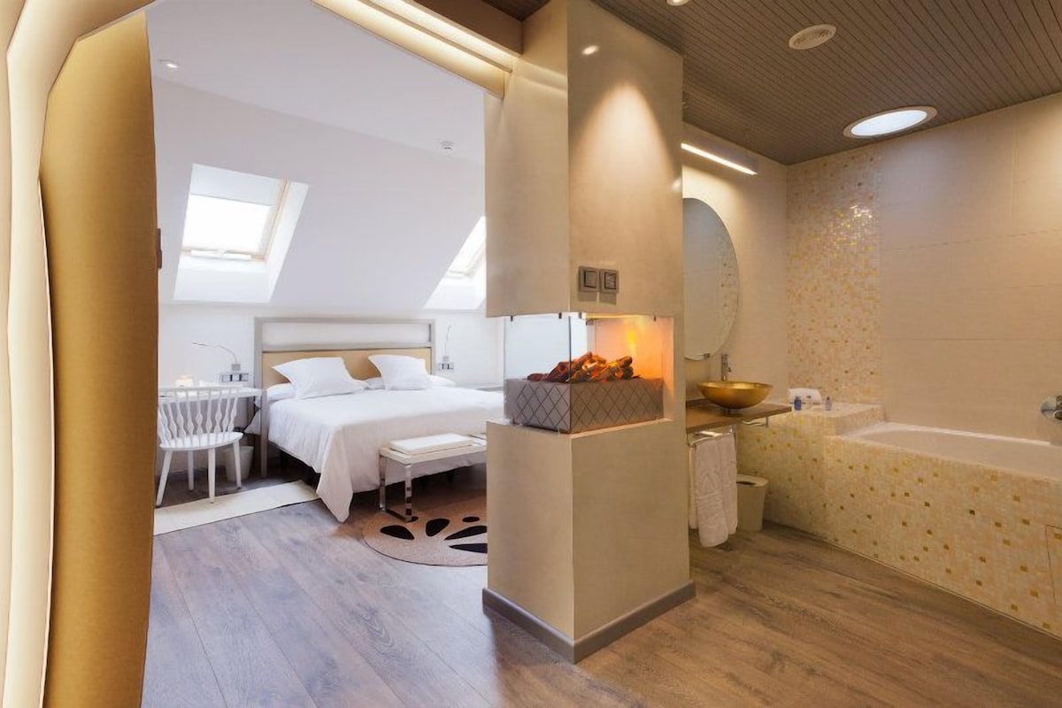 A bedroom with a bed, bedside table, and a small seating area.