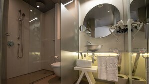 Une salle de bain moderne avec une douche à parois de verre, des toilettes, un lavabo avec un miroir et un porte-serviettes.