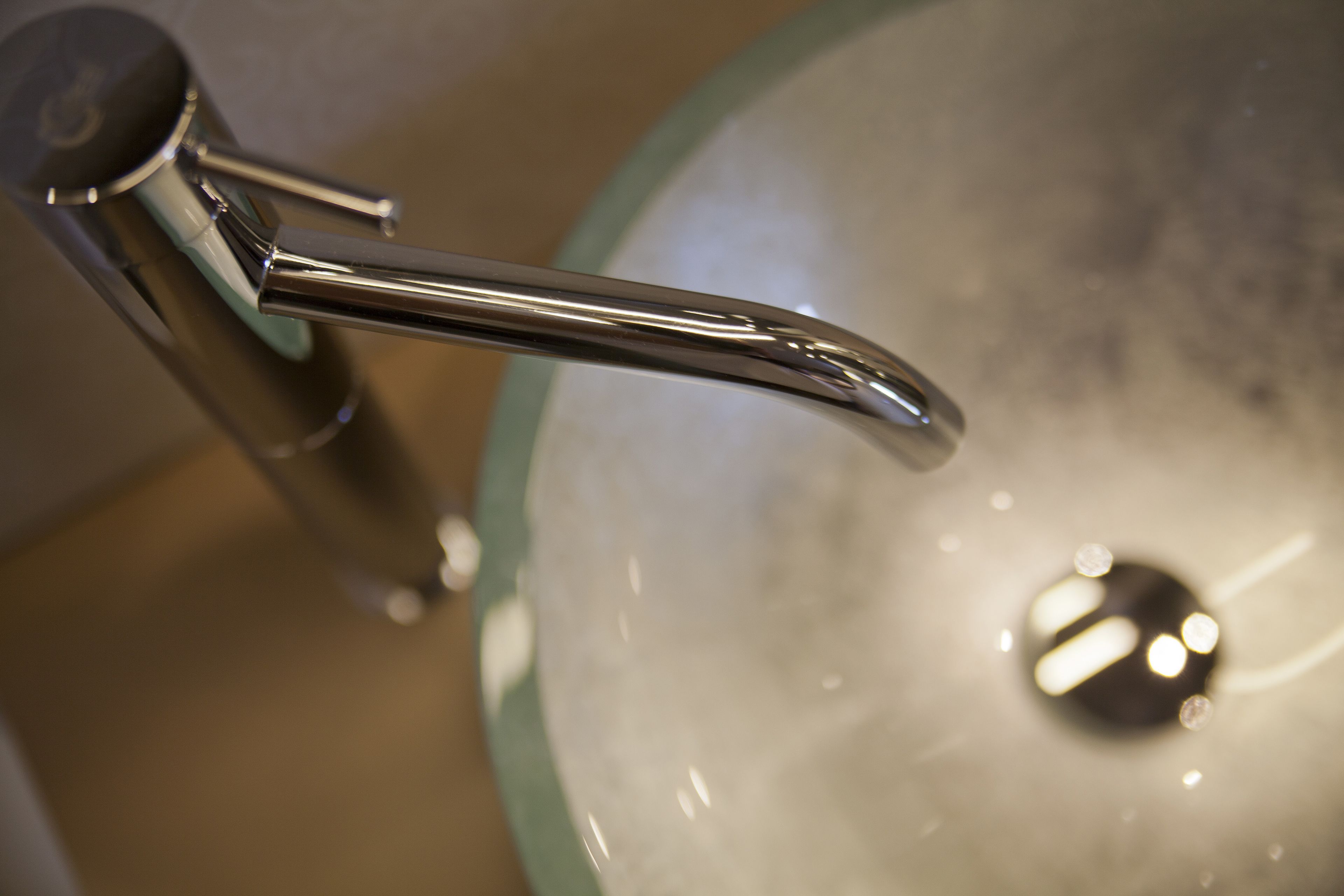A bathroom sink with a chrome faucet and a glass basin.