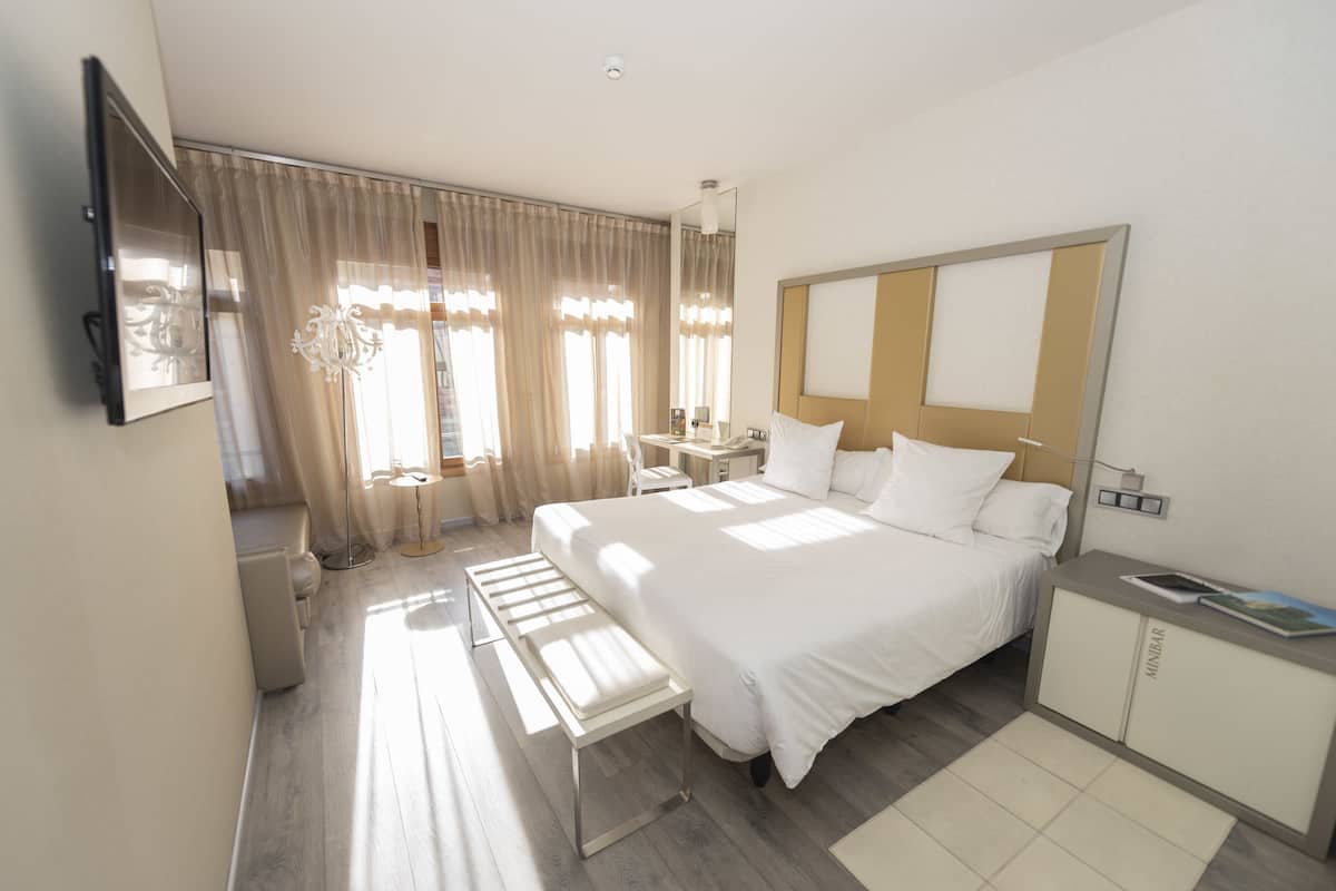 Ein Hotelzimmer mit Bett, Nachttisch, Lampe und Spiegel.