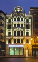 Un hotel imponente con fachada clásica, varios balcones y una entrada destacada.