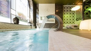 Une piscine intérieure moderne avec un élément décoratif à l’eau claire, une statue de Bouddha et une horloge murale.