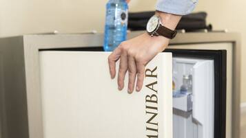A hand reaching into a minibar with the word "MINIBAR" visible on the door.