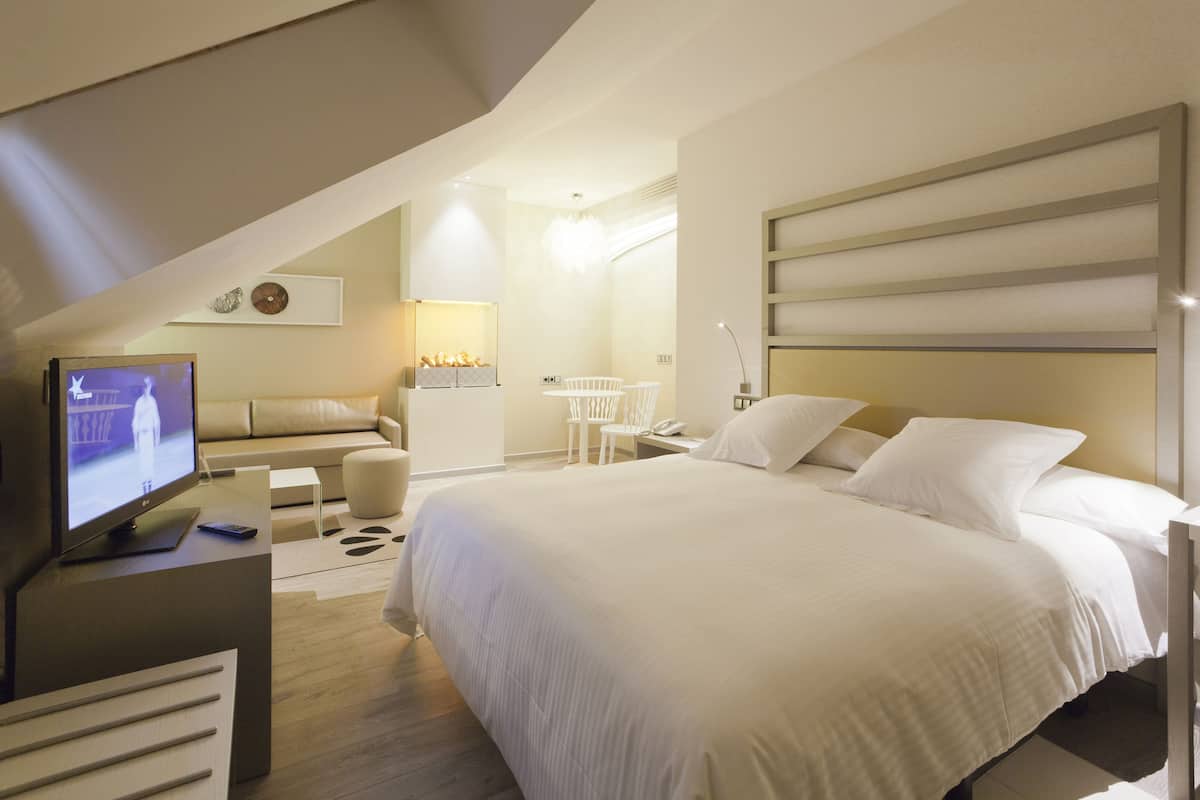 Ein modernes Hotelzimmer mit einem großen Bett, einem Fernseher, einem Schreibtisch und einem Sessel.
