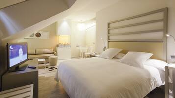 A modern hotel room with a large bed, a TV, a desk, and a chair.