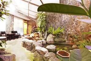A room with a stone wall, a small pond, and various plants. - Emperor Hotel (Taipei)